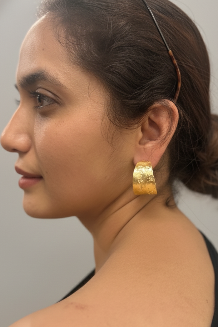 Woman wearing gold hoop earrings with a neutral background