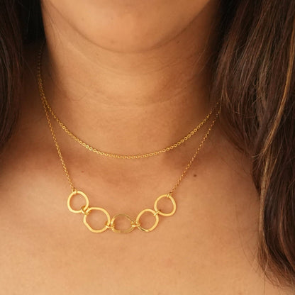 A person wearing a gold-plated necklace with sterling silver and a chain length of 18 inches, layered with another necklace.