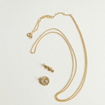Gold necklace with a pendant on a light gray background