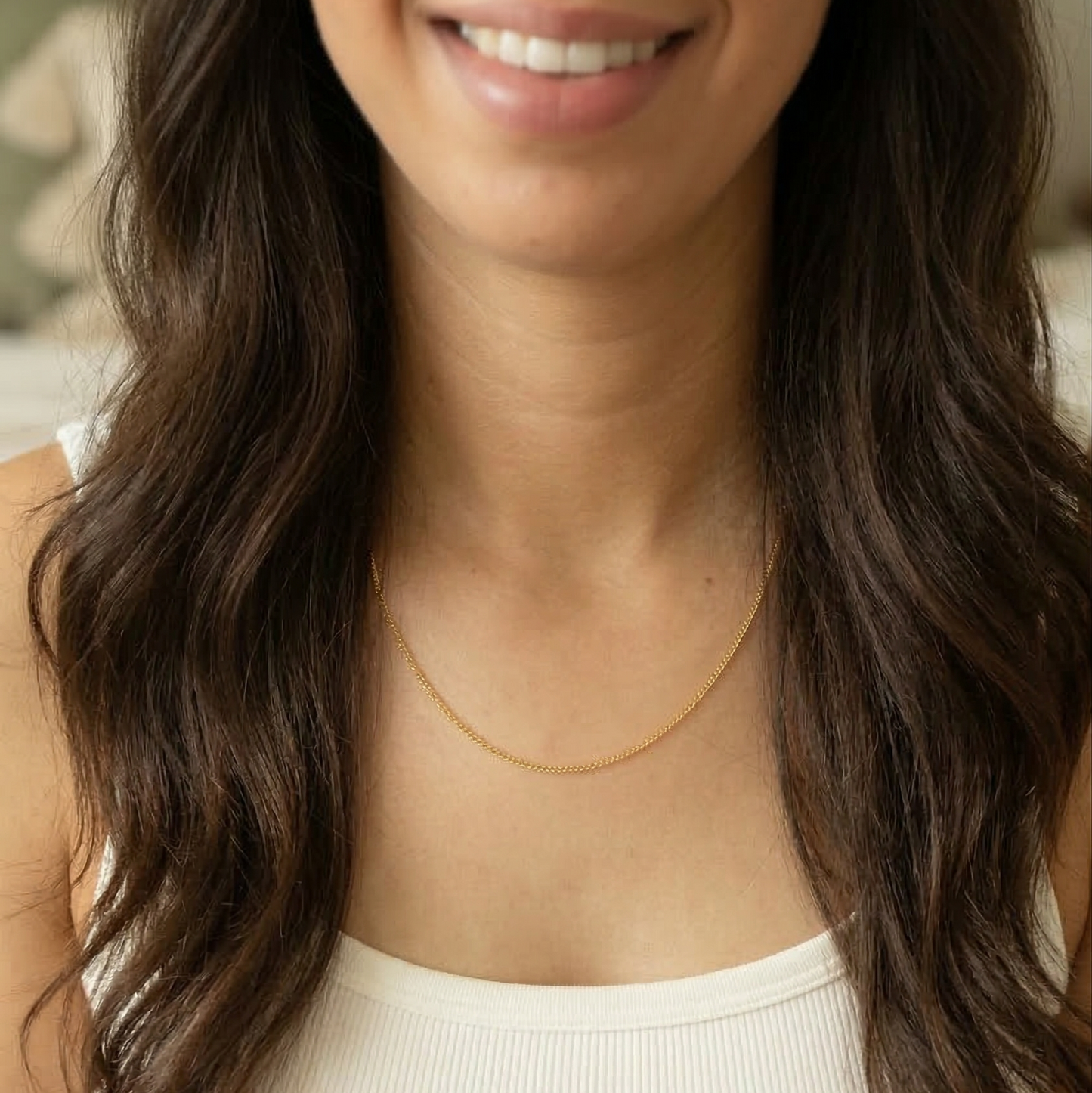 Woman wearing a gold necklace with a neutral background