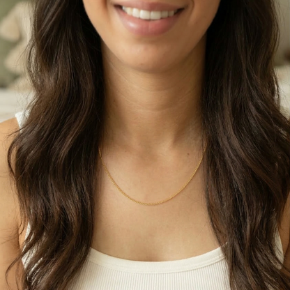 Woman wearing a gold necklace with a neutral background