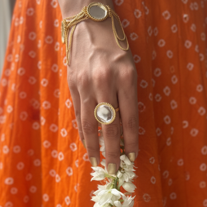 Person wearing an orange traditional outfit with a gold bracelet and ring, holding a white flower garland.