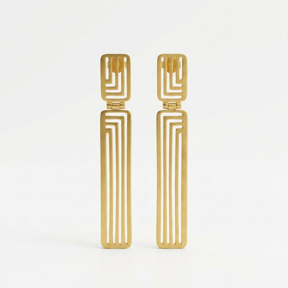 A pair of gold-toned geometric drop earrings with a rectangular top and a long, narrow vertical bar featuring parallel cutout lines, shown on a plain white background.