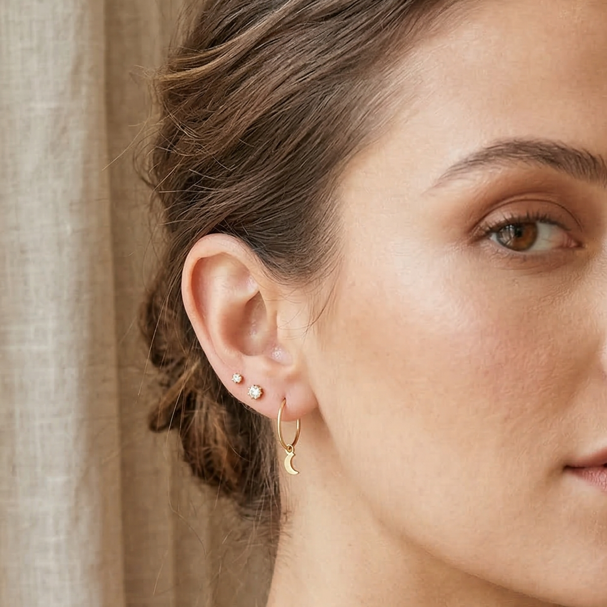Woman with styled hair and earrings in a neutral setting