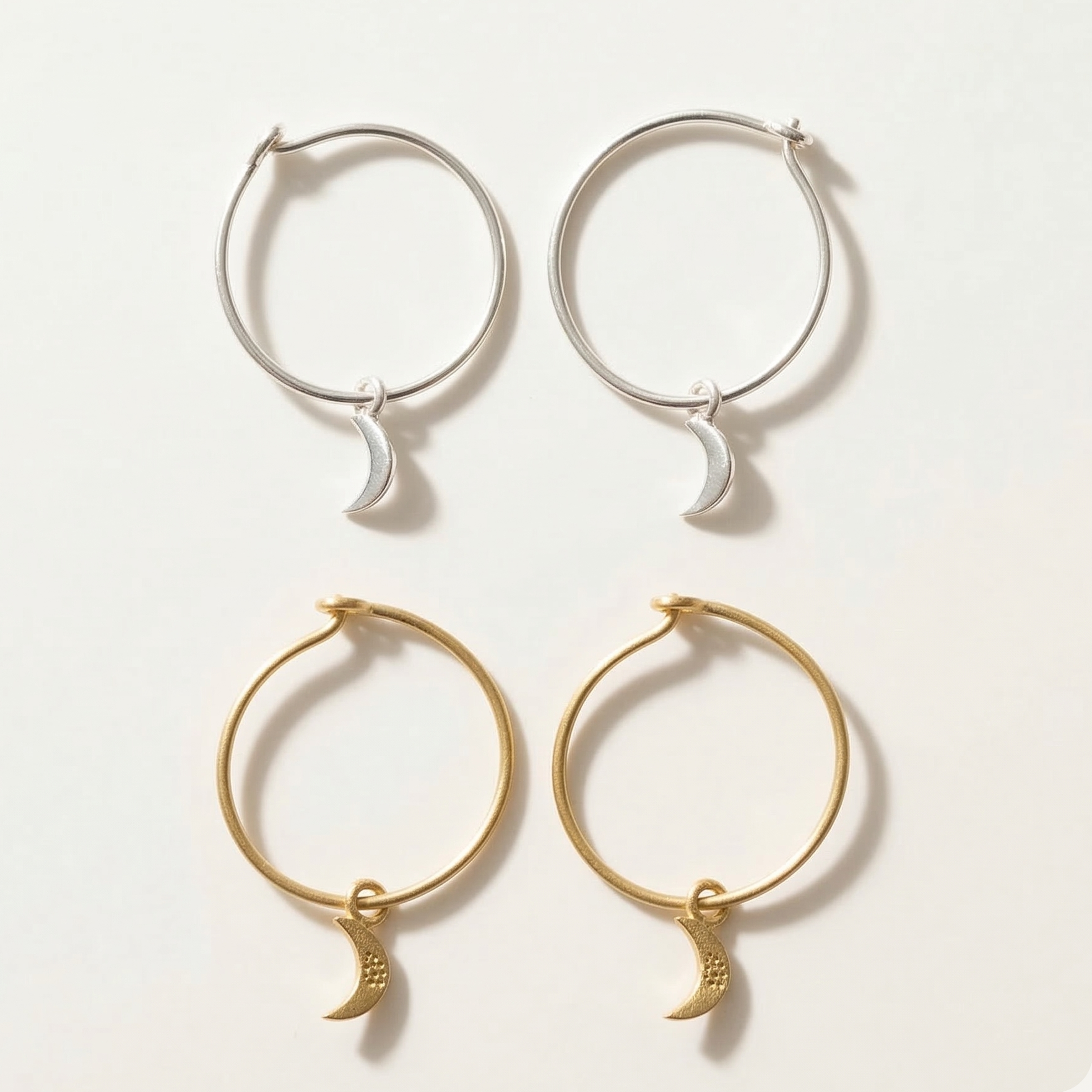 Set of gold and silver hoop earrings with moon charms on a light background