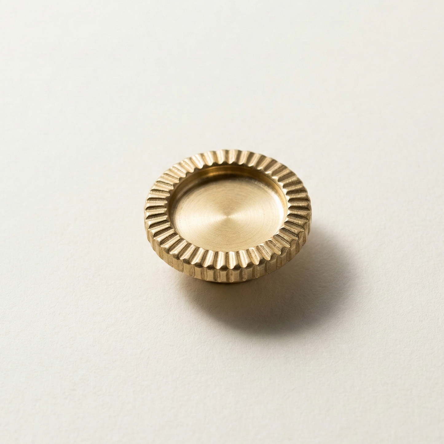 Gold brooch with textured surface on a light beige background