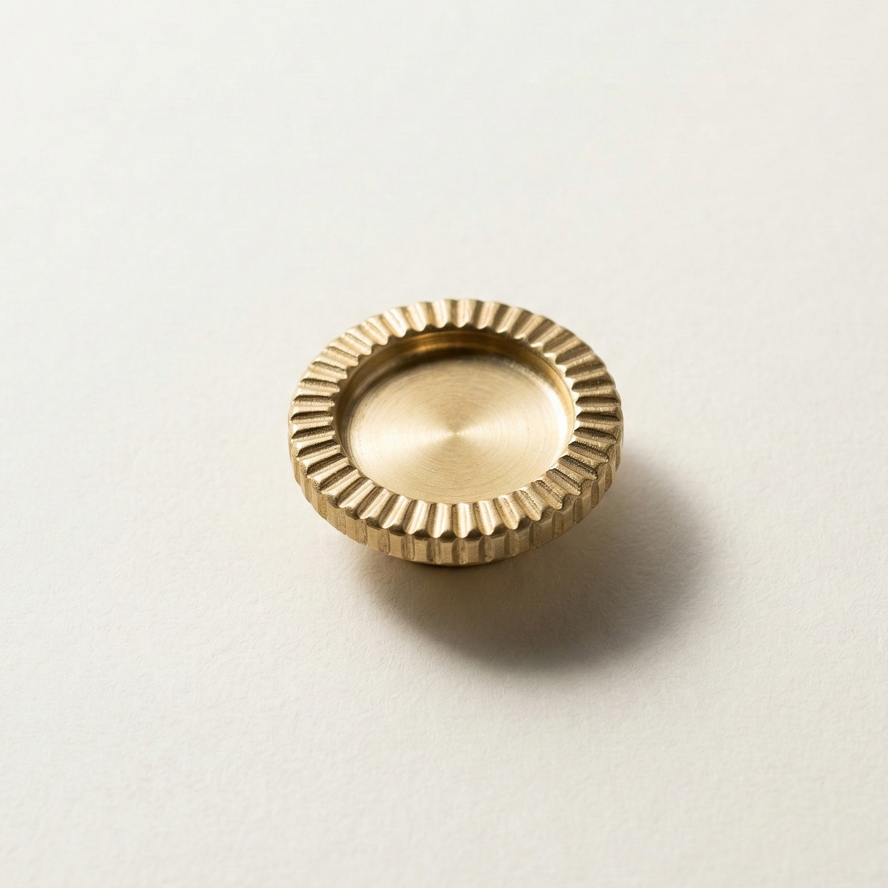 Gold brooch with textured surface on a light beige background