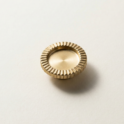 Gold brooch with textured surface on a light beige background