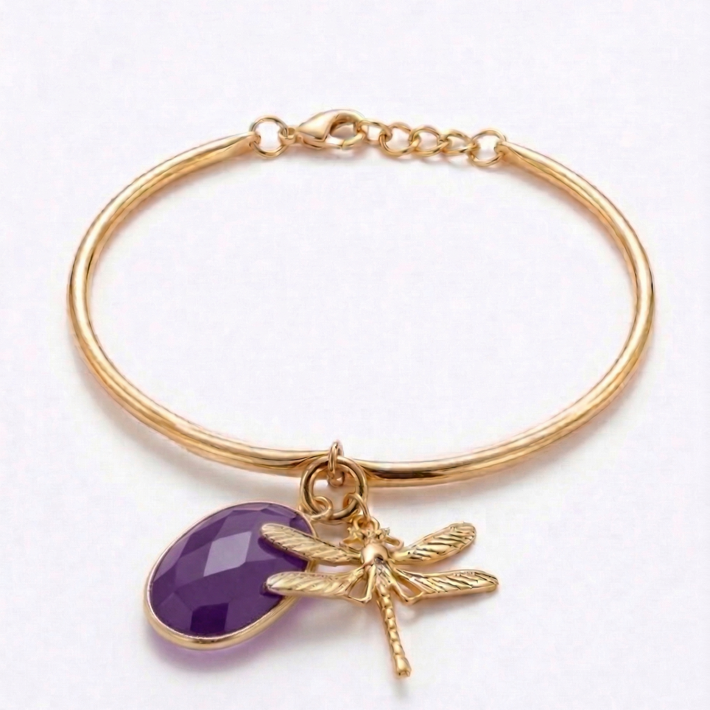 Gold bracelet with purple stone charm and dragonfly detail on a white background