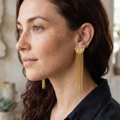 Woman wearing gold earrings with a neutral background