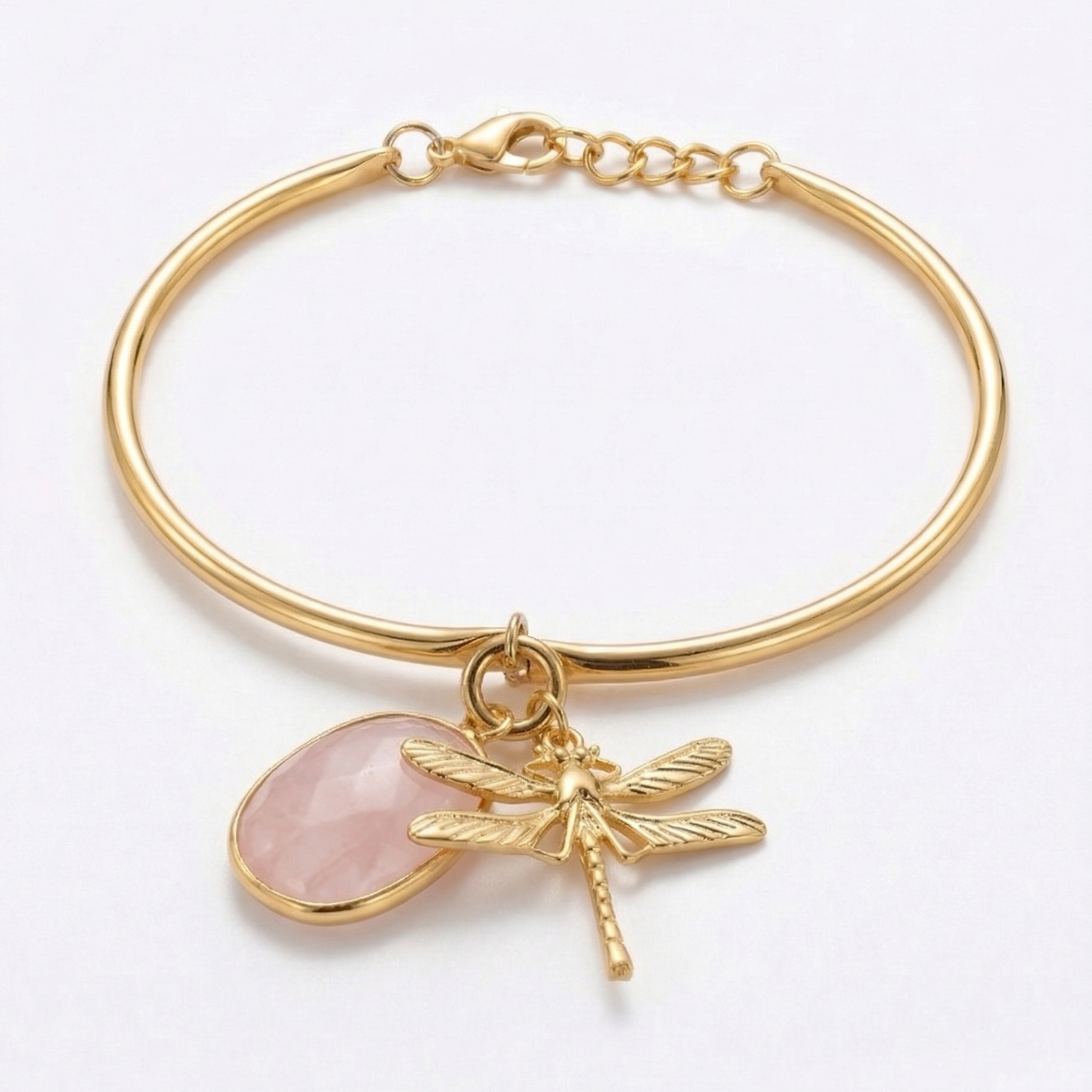 Gold bracelet with a pink stone and dragonfly charm on a white background
