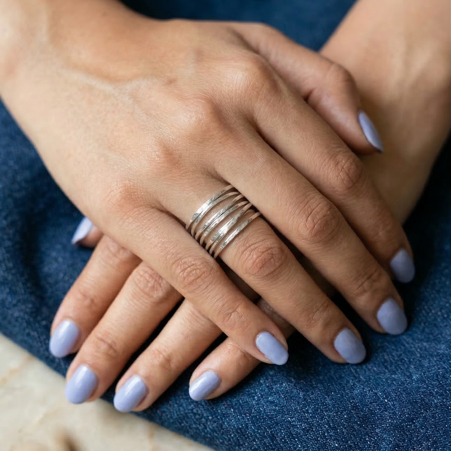 Close-up of hands with silver rings on a blue fabric background