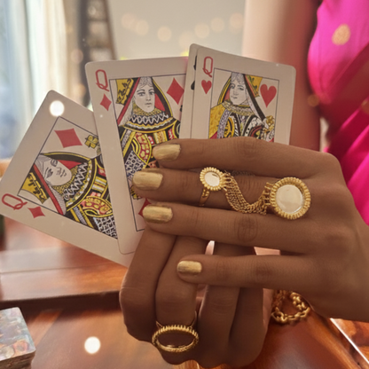 Hand holding playing cards with statement gold silver ring for women.