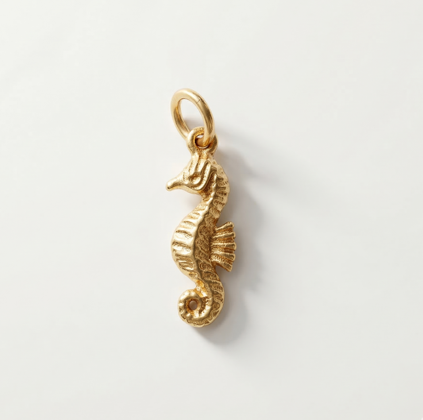 Gold seahorse pendant on a light gray background