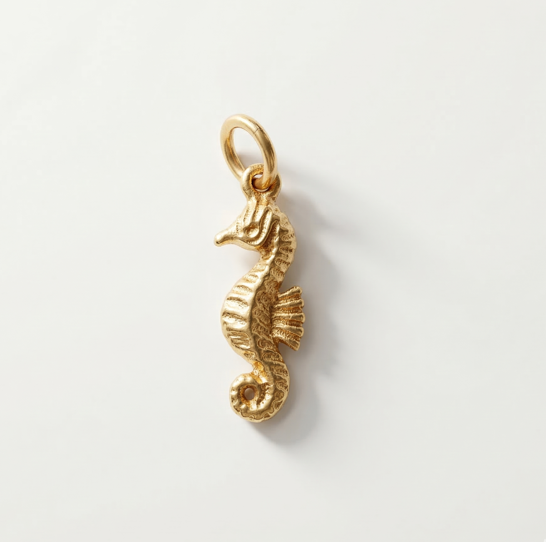 Gold seahorse pendant on a light gray background