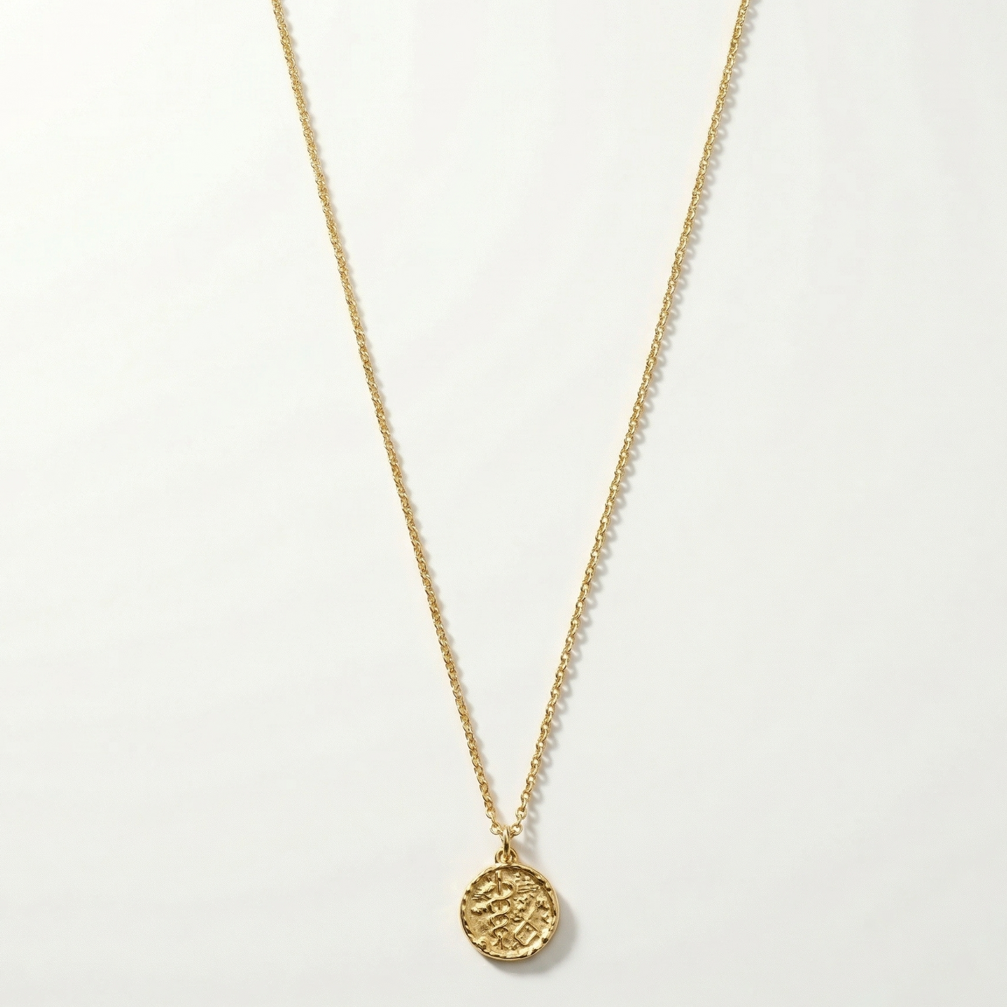 Gold necklace with a round pendant on a white background