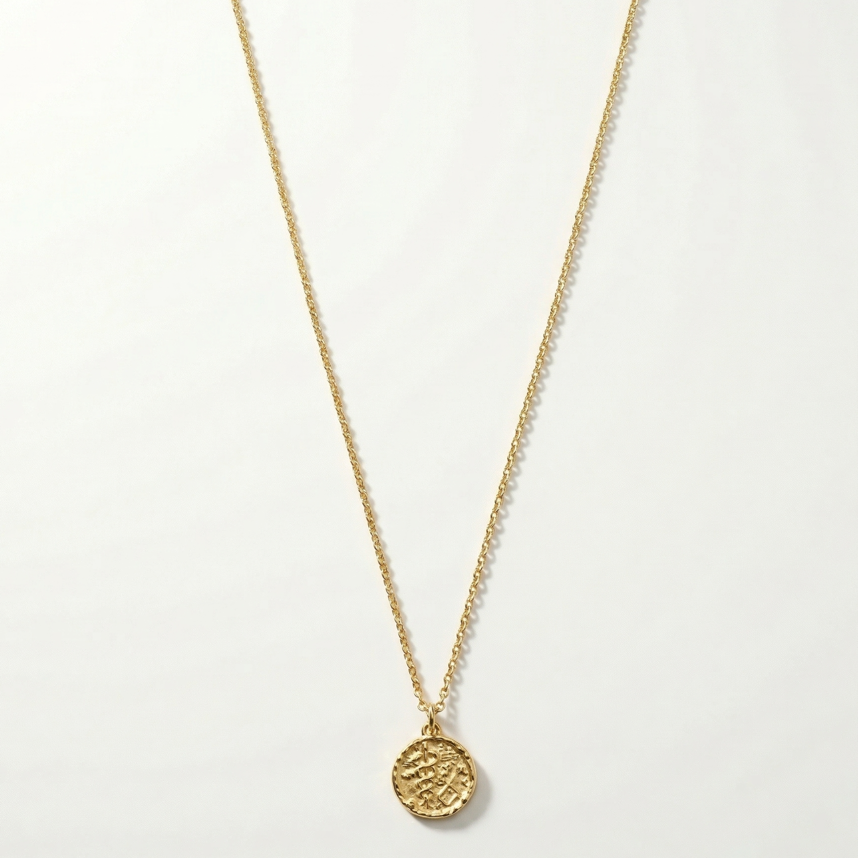 Gold necklace with a round pendant on a white background