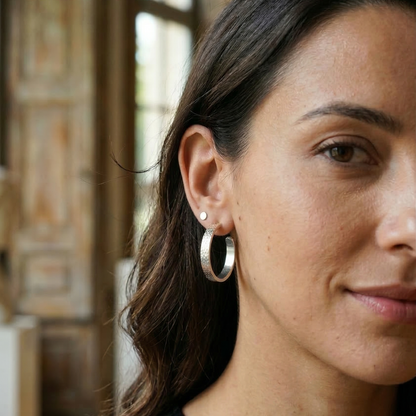 Close-up of a woman wearing silver hoop earrings with a blurred background