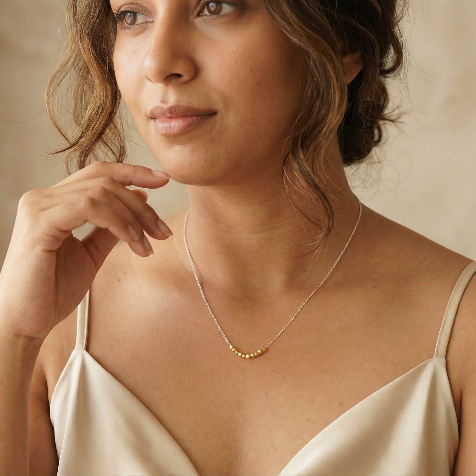 Woman wearing a gold necklace against a neutral background