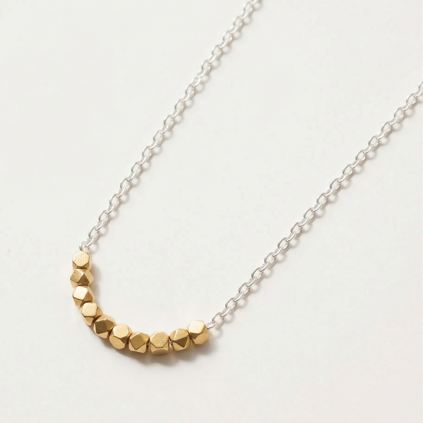 Necklace with gold beads on a silver chain against a white background