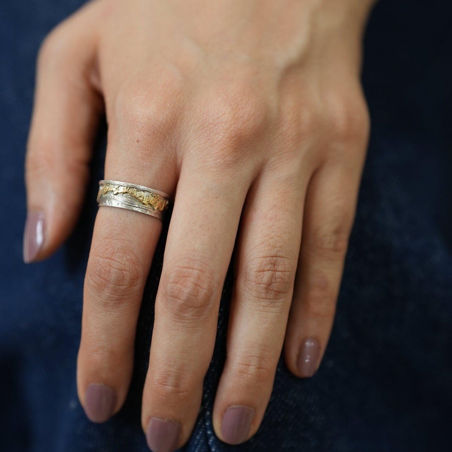 Hand wearing a gold ring with a dark background