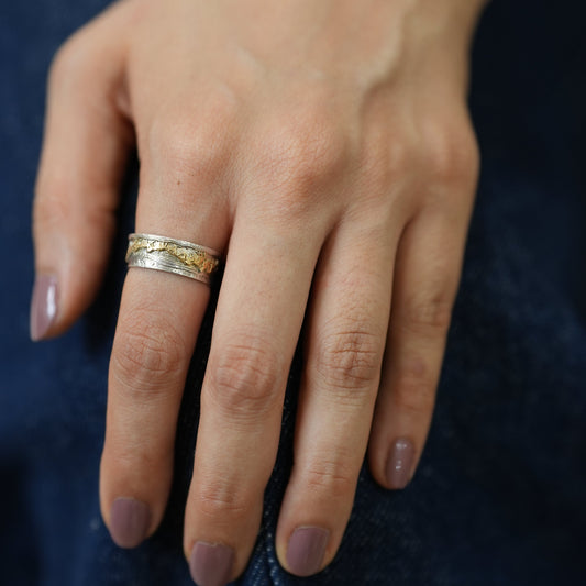 Hand wearing a gold ring with a dark background