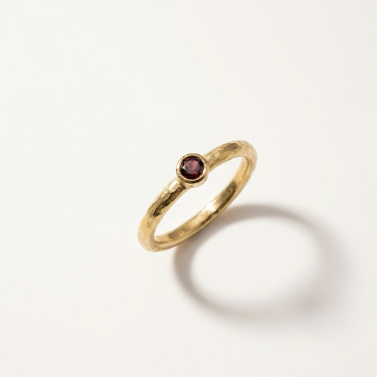 Gold ring with a garnet gemstone on a white background
