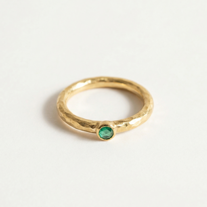 Gold ring with a green onyx  gemstone on a light gray background