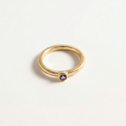 Gold ring with a iolite gemstone on a light gray background