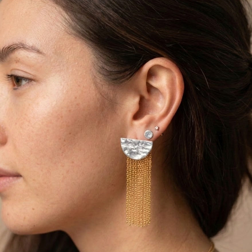 Close-up of a woman wearing gold earrings with a neutral background