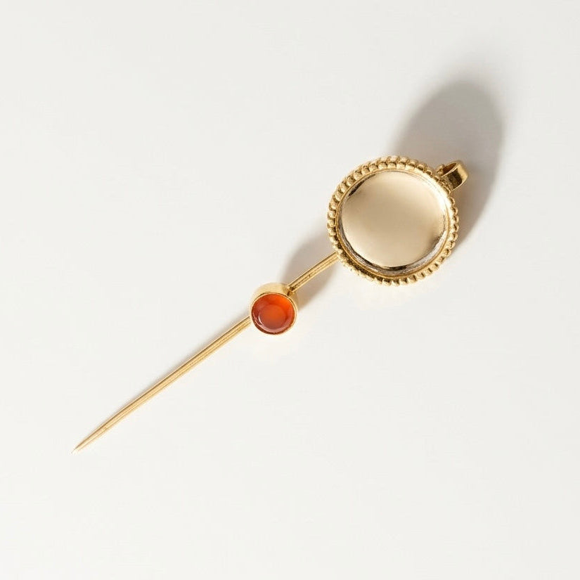 Gold and silver earpin with a clear gemstone and carnelian stone on a light gray background
