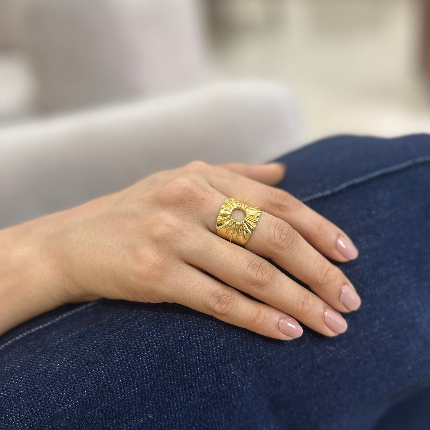 Hand wearing a gold ring with a sun design 