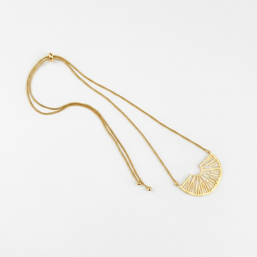 A gold-toned necklace featuring a delicate chain and a semi-circular fan-shaped pendant with radiating linear details, displayed on a clean white background.