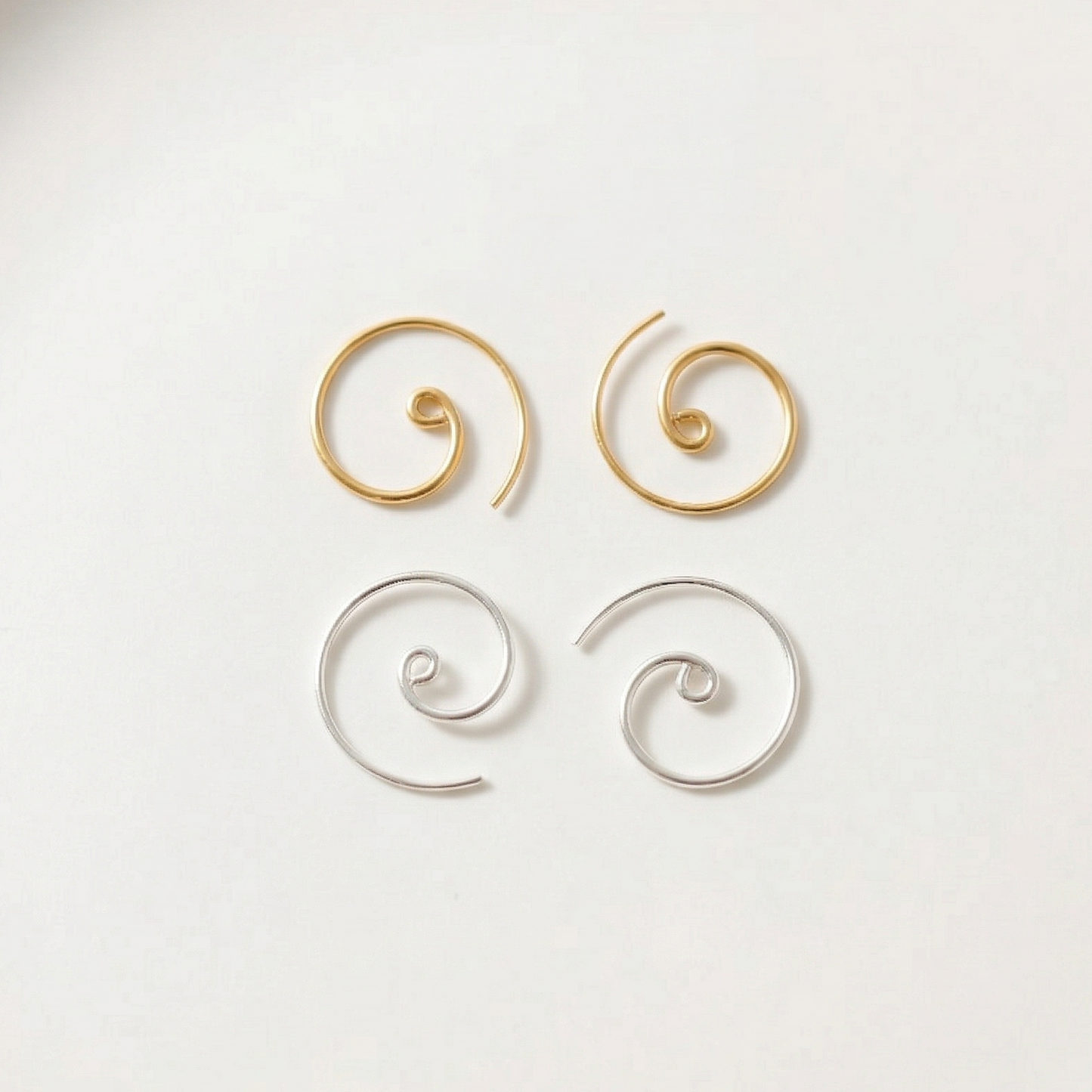 Pair of gold spiral earrings on a white plate