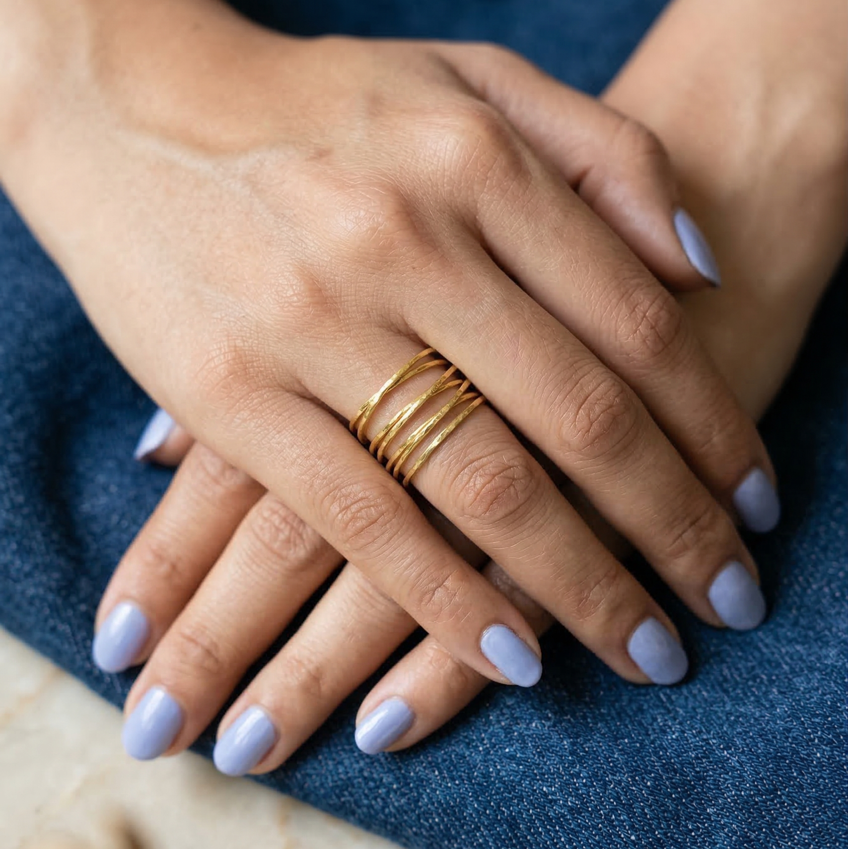 Close-up of hands with gold rings on a blue fabric background