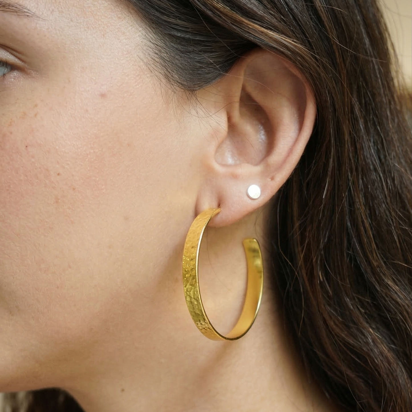 Close-up of a person wearing a gold hoop earring.