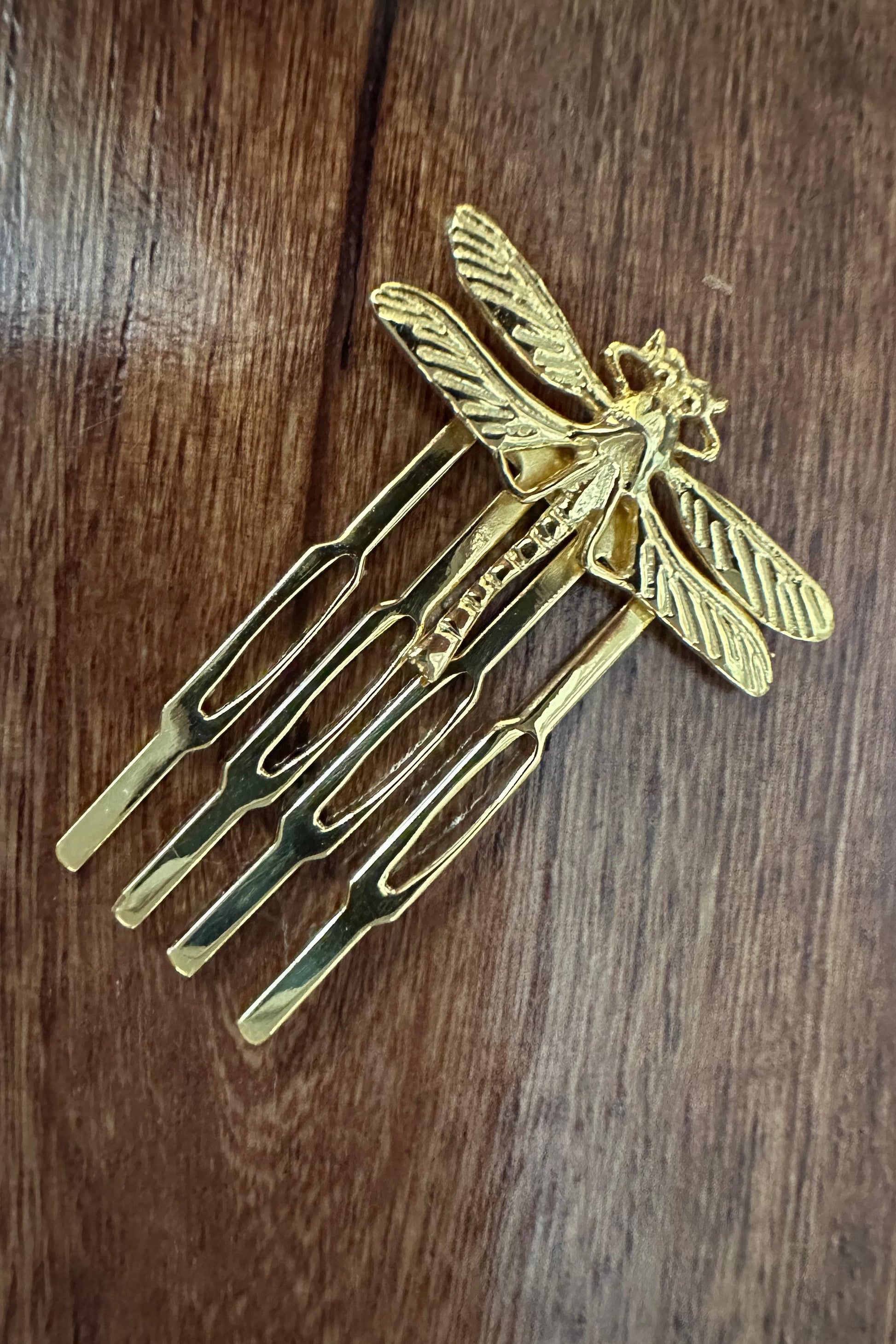 Gold dragonfly-shaped hairpin on a wooden surface