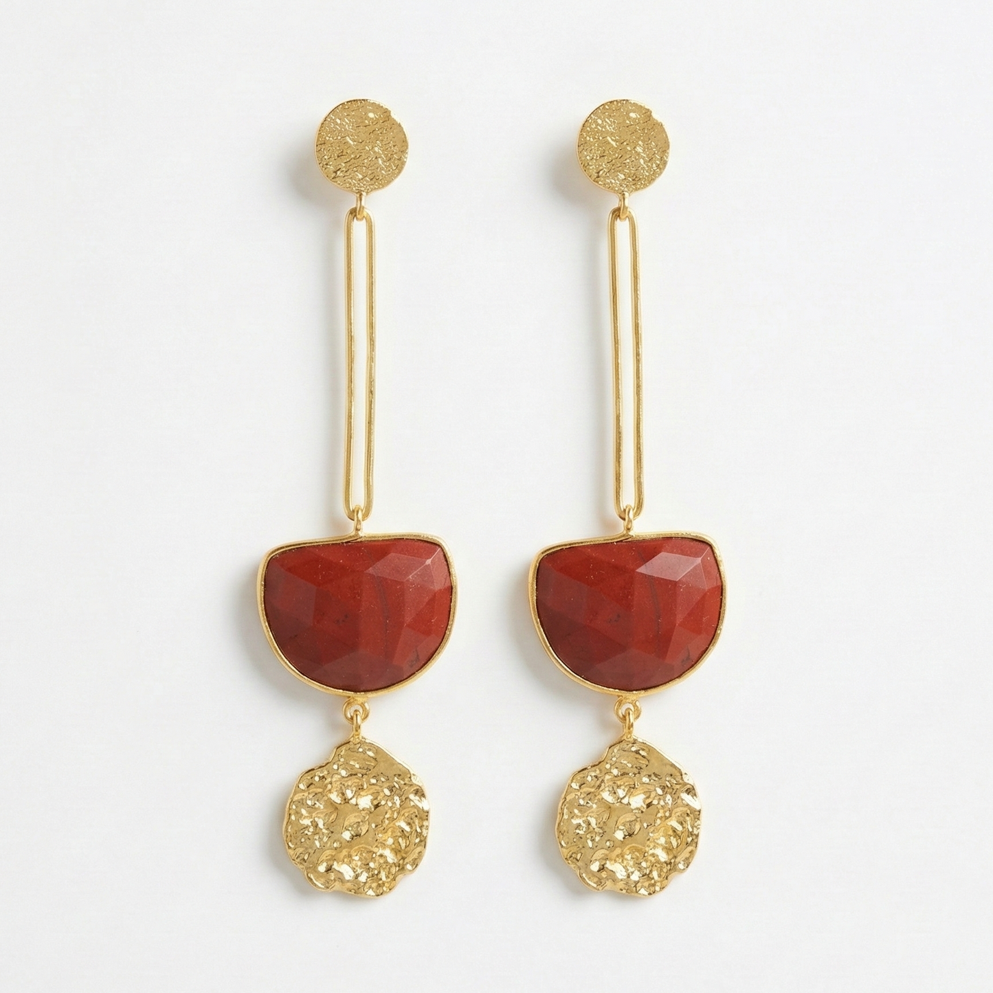 Gold earrings with red stones on a white background