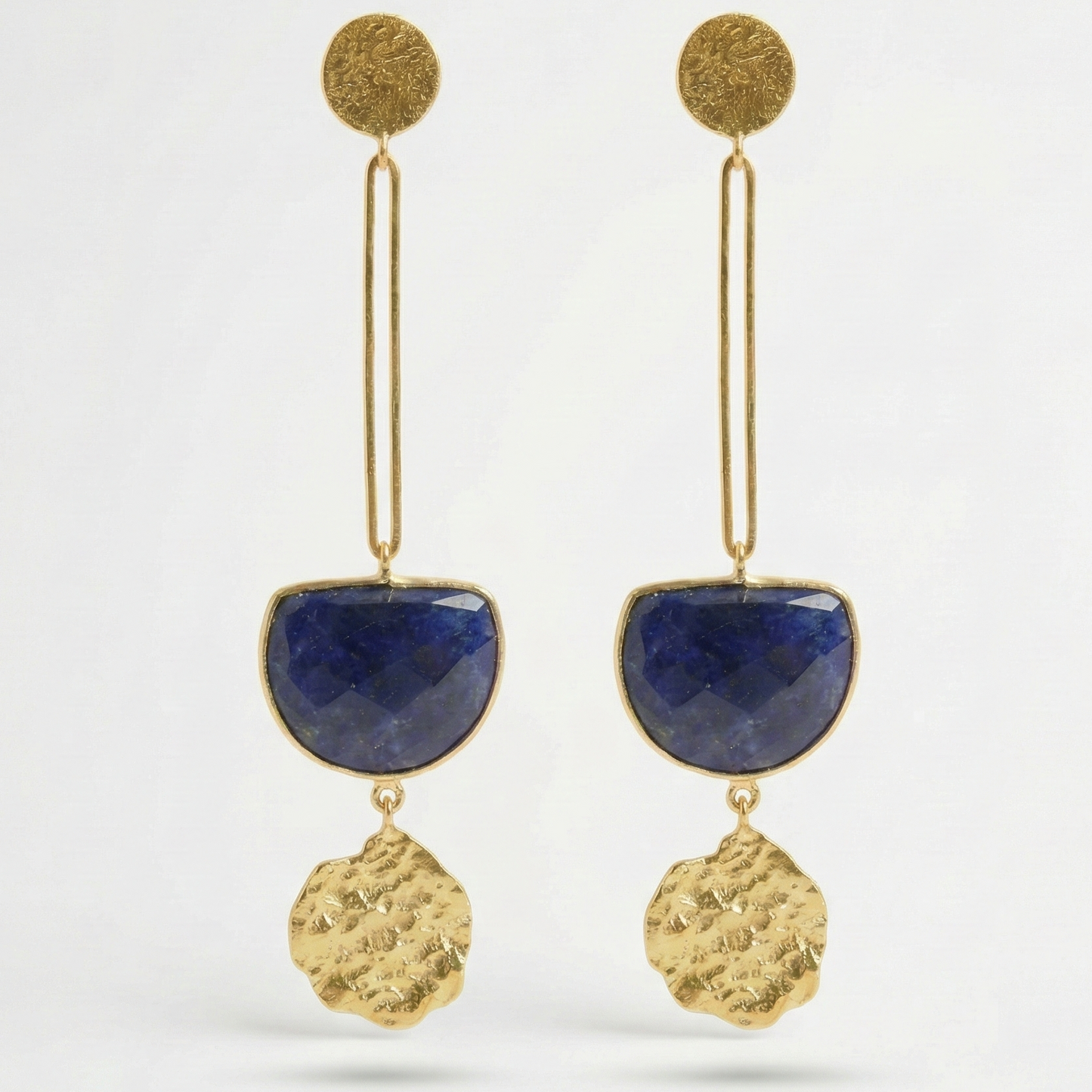 Gold earrings with blue sodolite semi-precious stones on a white background
