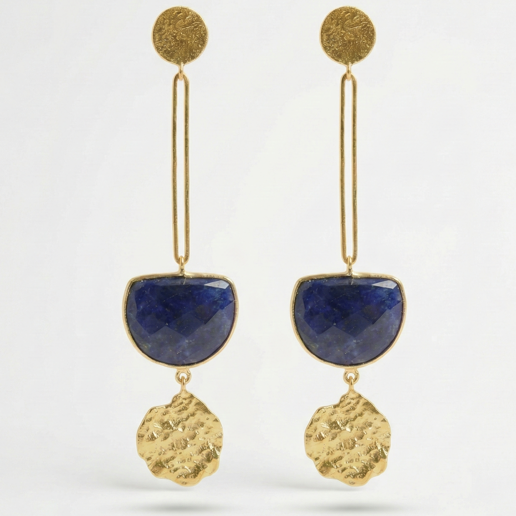 Gold earrings with blue sodolite semi-precious stones on a white background