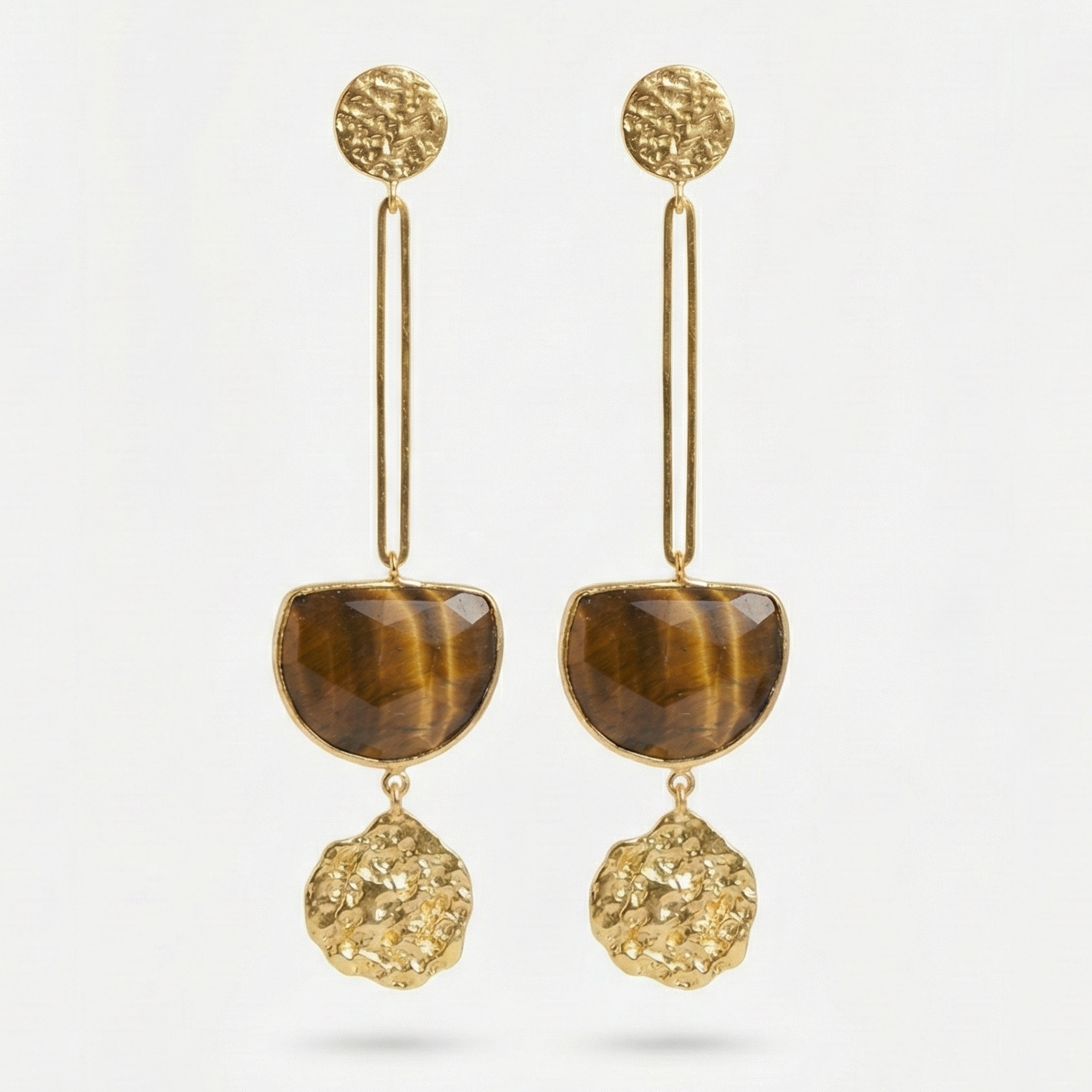 Pair of gold earrings with tiger's eye stones on a light gray background