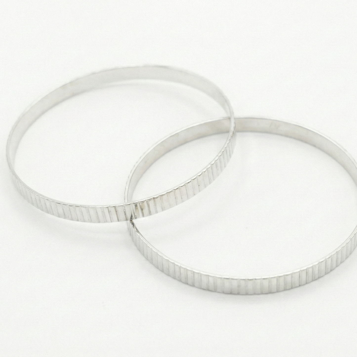 Silver lined textured bangles on a white background