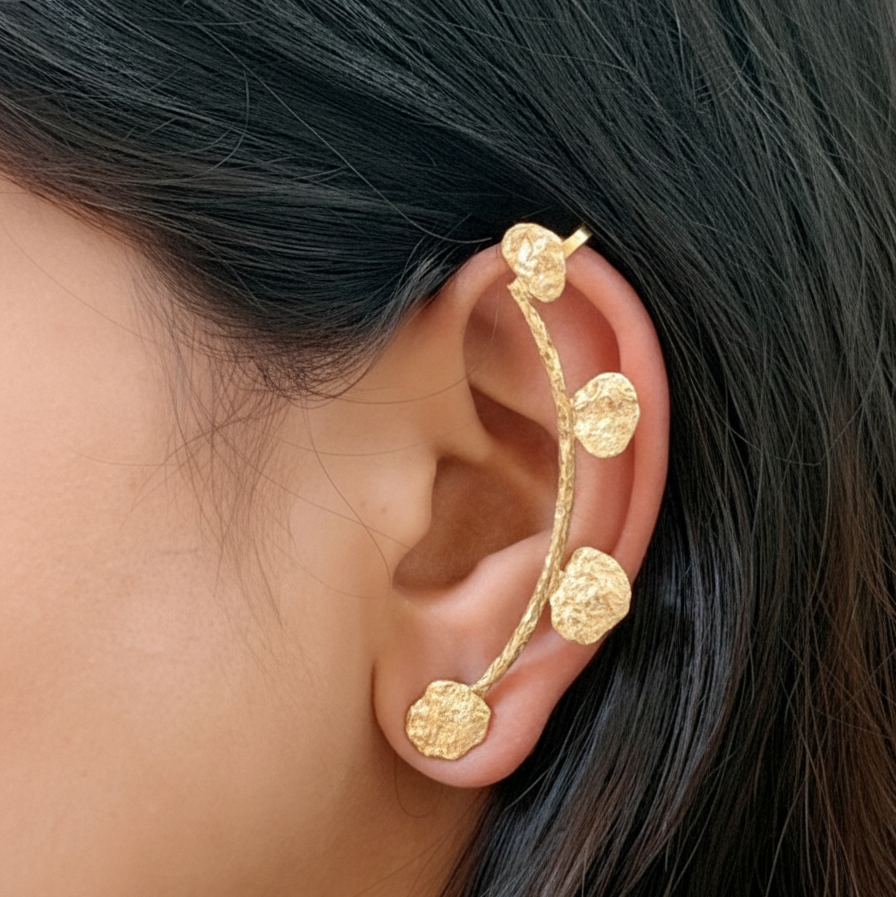 Gold ear cuff worn by a person with dark hair