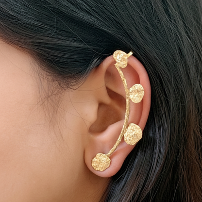 Gold ear cuff worn by a person with dark hair