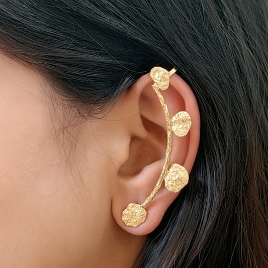 Gold ear cuff worn by a person with dark hair